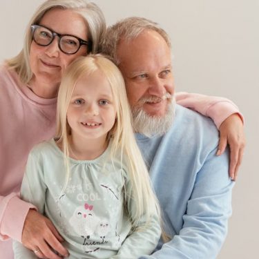 An affectionate family moment featuring grandparents and their granddaughter smiling together.