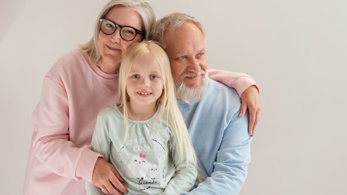 An affectionate family moment featuring grandparents and their granddaughter smiling together.